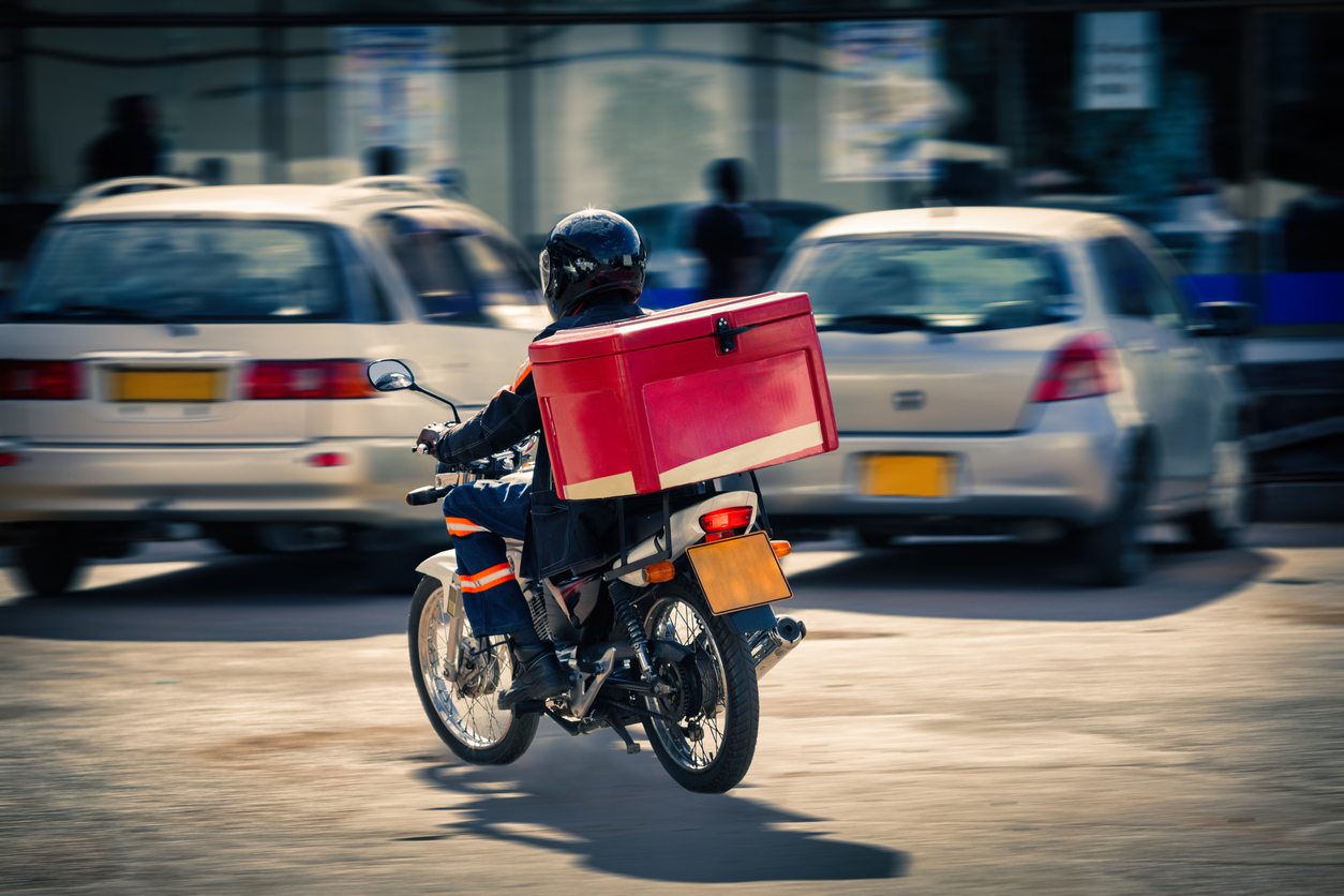 Dispatch rider on a motorcycle delivering a parcel in a Nigerian city